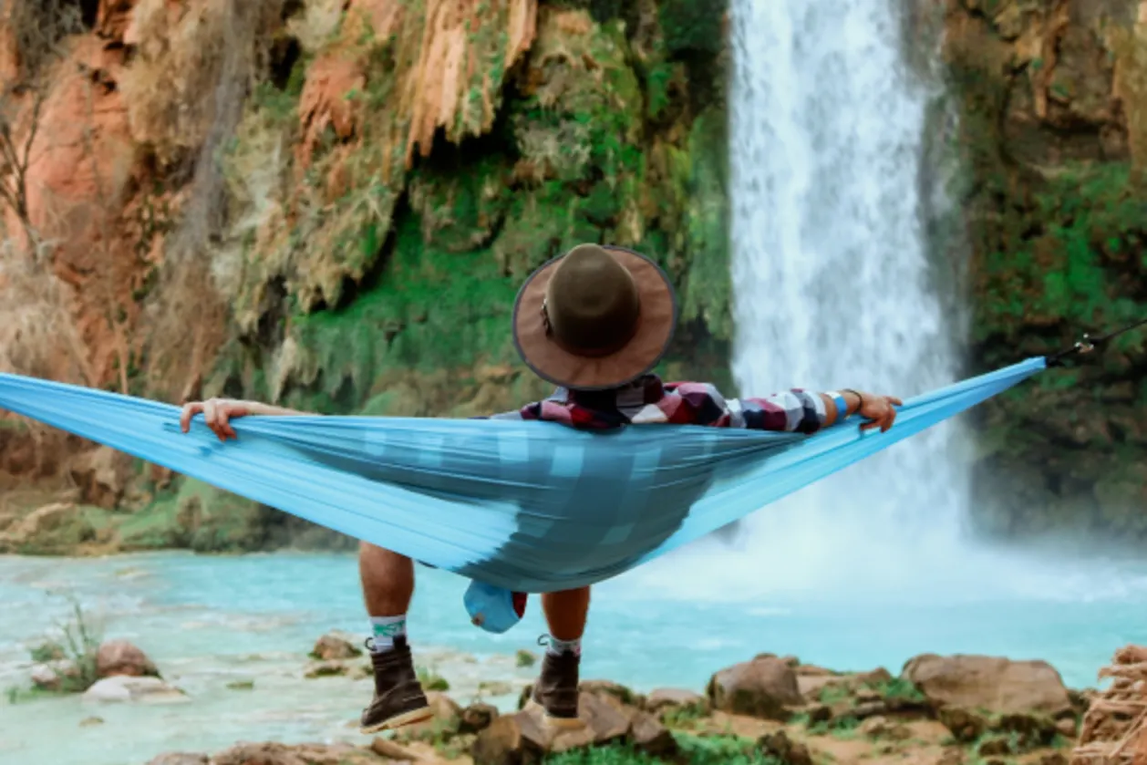 man on hammock in front of waterfall